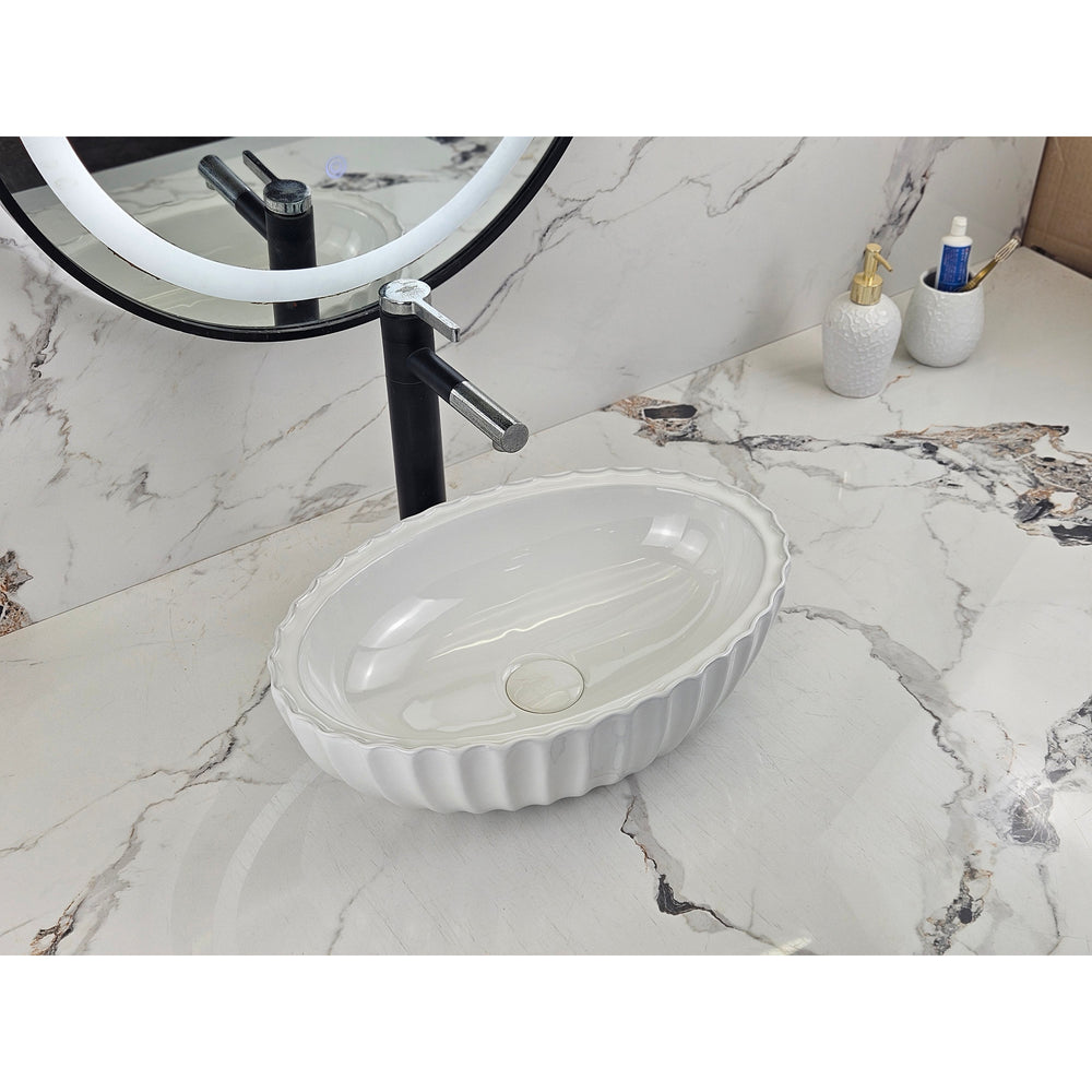 Infinity IA102 oval fluted gloss white basin installed on a marble vanity, angled view